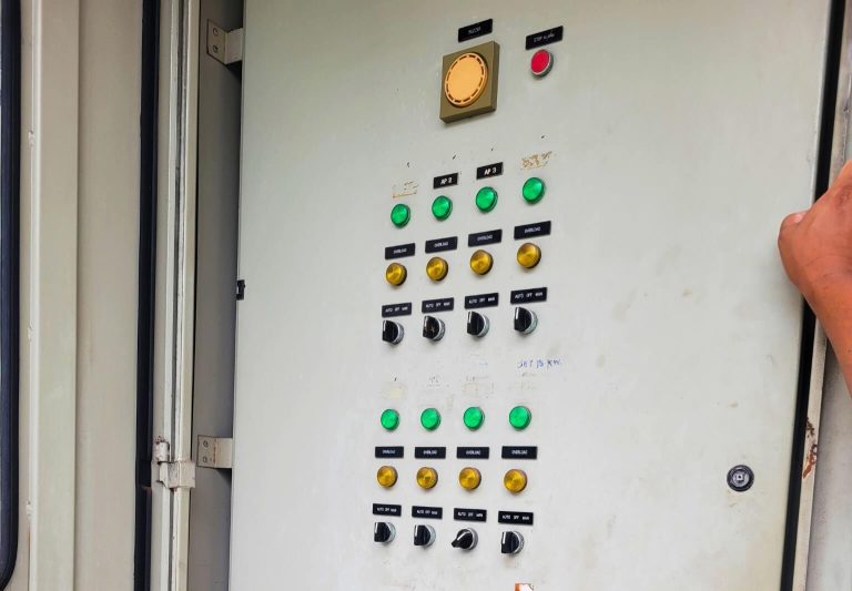 HydroNeo team checking the Industrial control panel in Thai Union Factory with multiple indicator lights, switches, and buttons inside an open enclosure