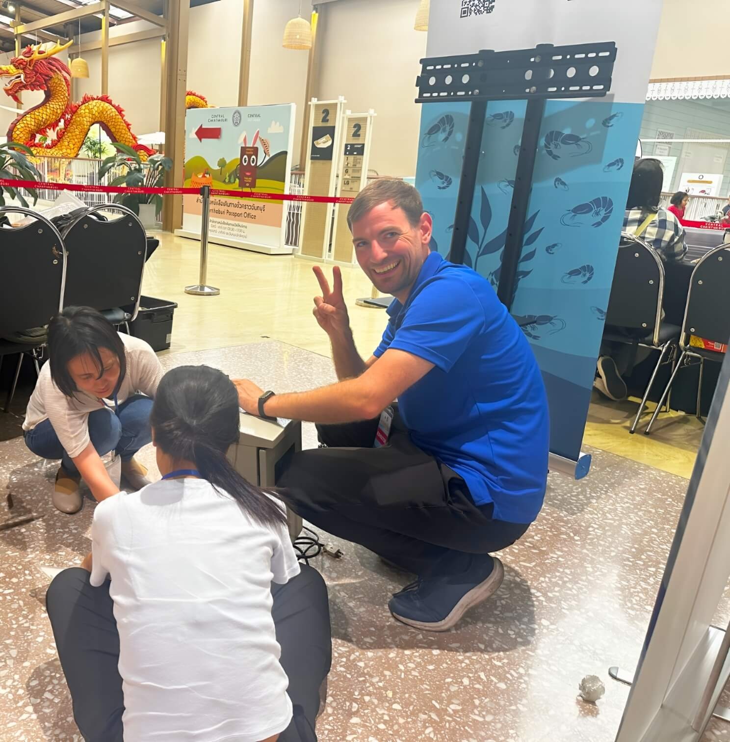 Our very own HydroNeo CEO and Founder Fabian Reusch smiling and posing with colleagues while sitting on the floor in a professional setting at an Expo event in Thailand